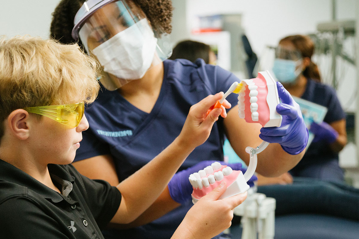 Dentist showing patient how to brush teeth